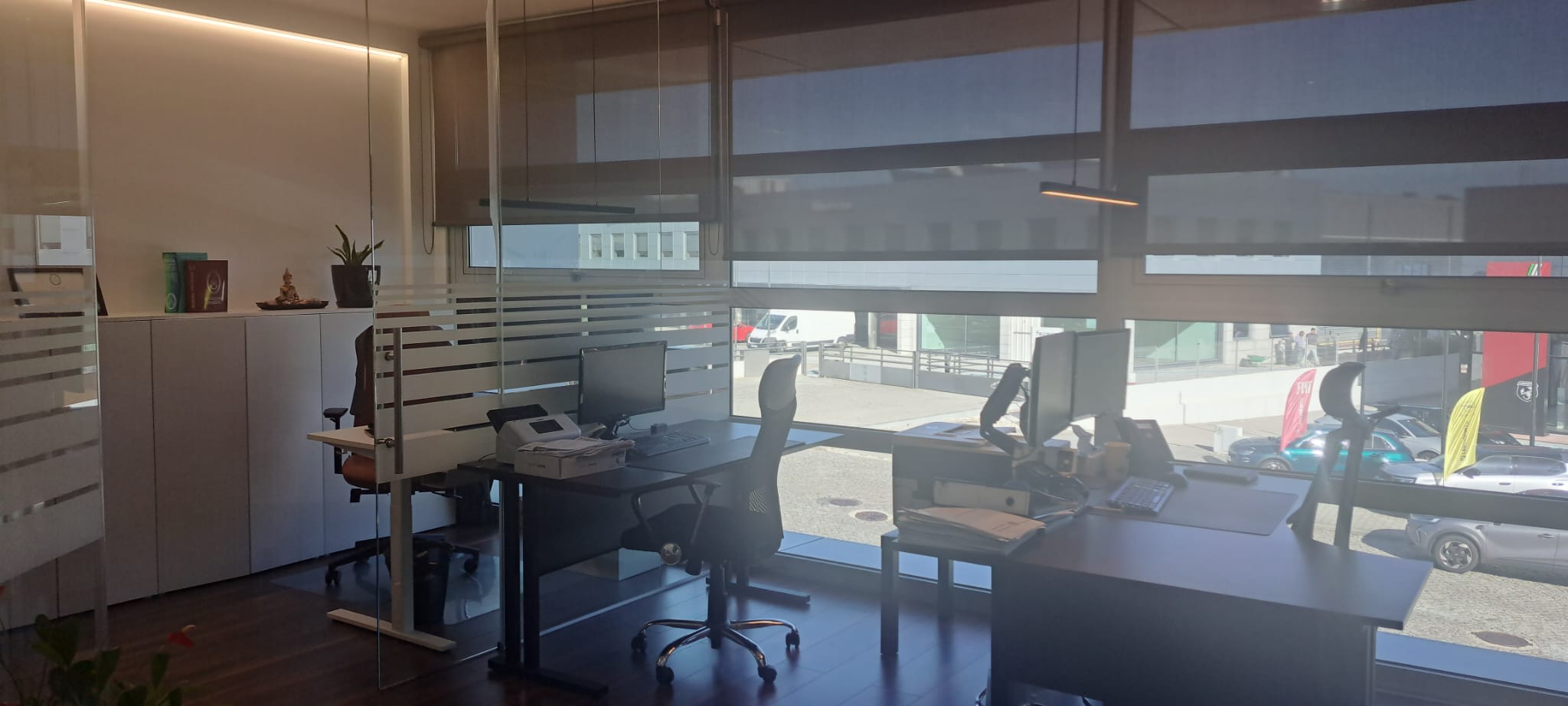 Escritório da +GREEN, com postos de trabalho junto às janelas e divisórias em vidro.